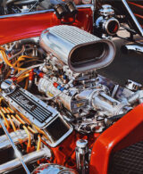 A red engine with yellow cables and an Edelbrock scoop on top